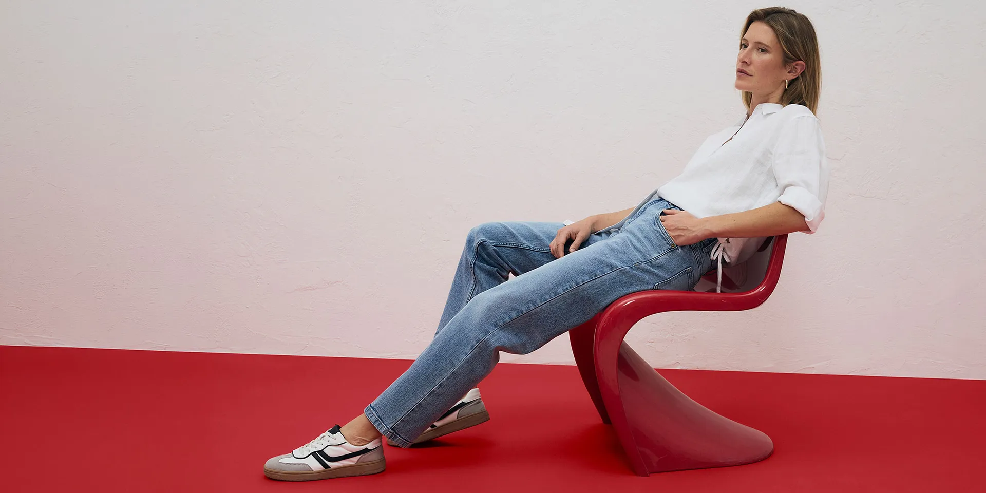 Camicia bianca e jeans azzurri, abbinati a sneakers.