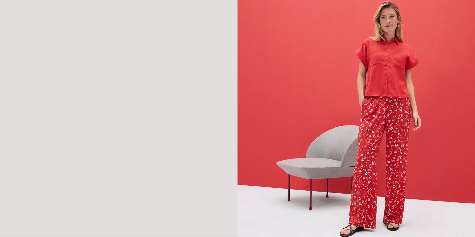 Camicia rossa a maniche corte e pantaloni fluidi con motivo floreale. Outfit estivo su sfondo rosso brillante.