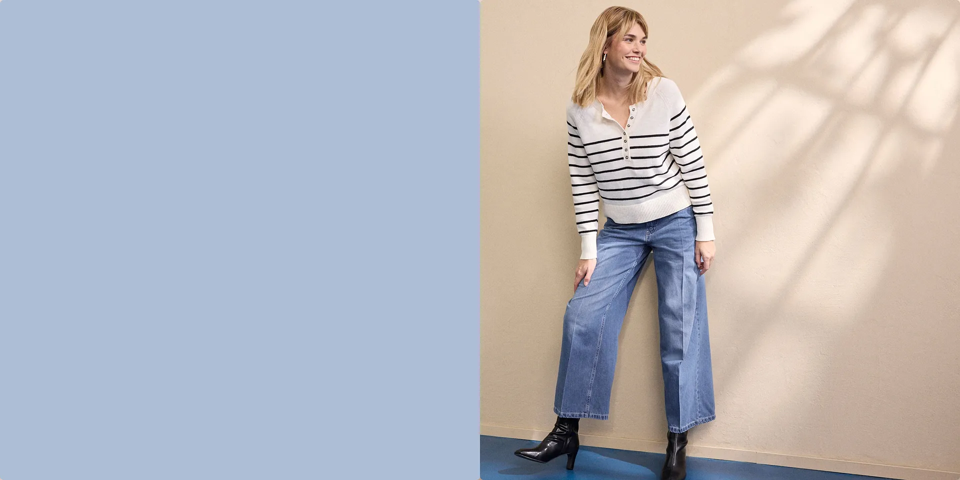 Maglione bianco a righe con cerniera, abbinato a jeans larghi e stivali neri.