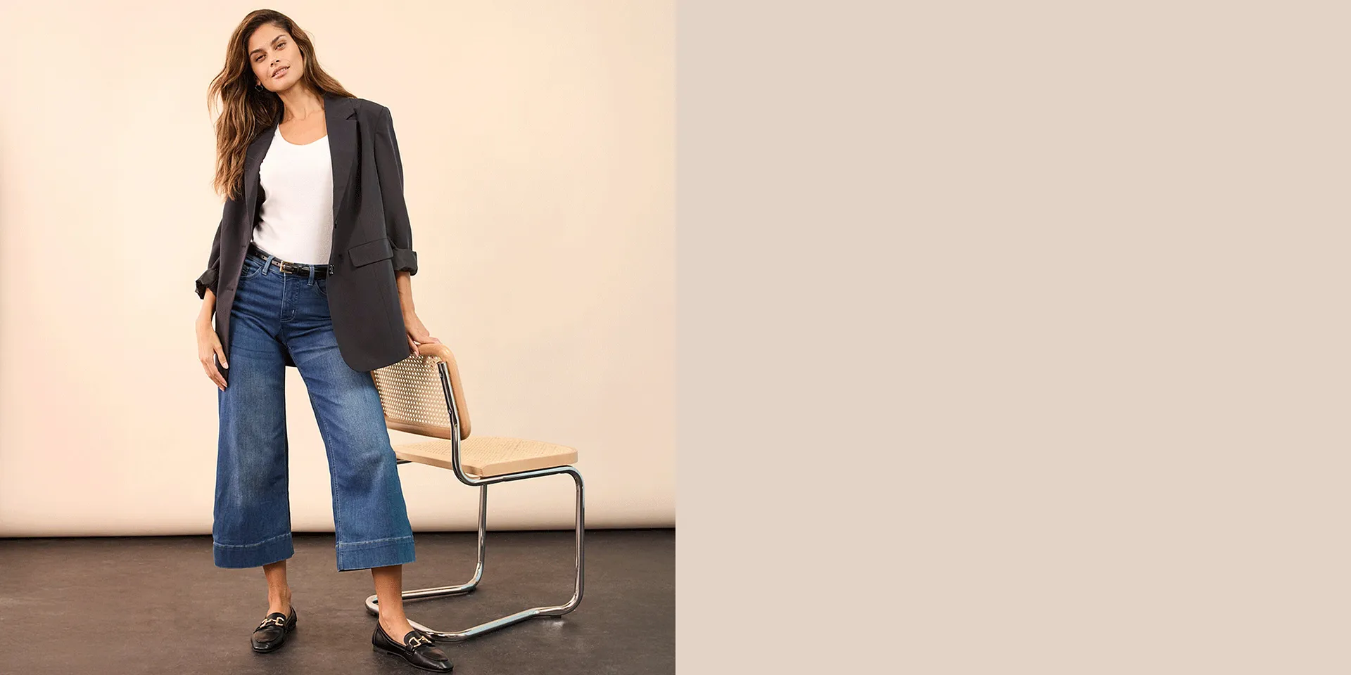 Elegante blazer grigio abbinato a top bianco, jeans larghi e mocassini neri.