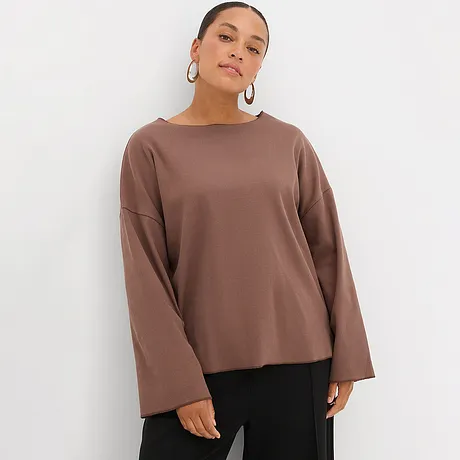 Maglia marrone a maniche lunghe e larghe, abbinata a pantaloni neri.