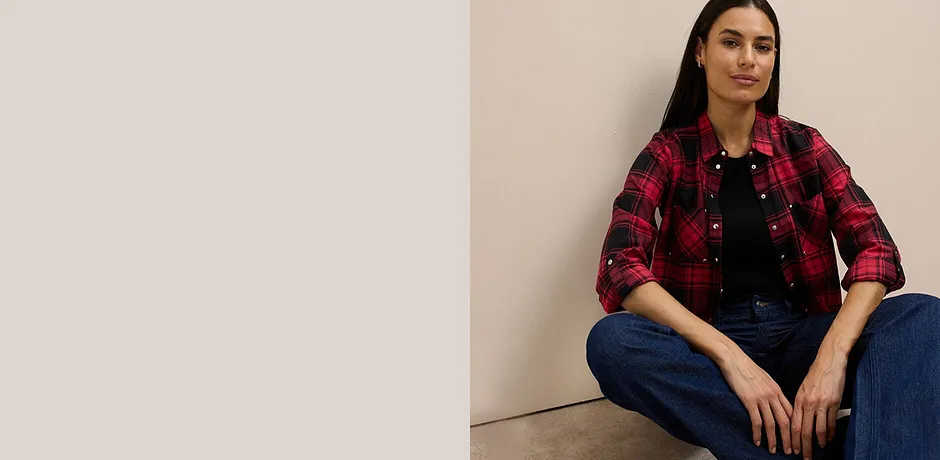 Camicia a quadri rossi e neri sopra un top nero, abbinata a jeans classici.