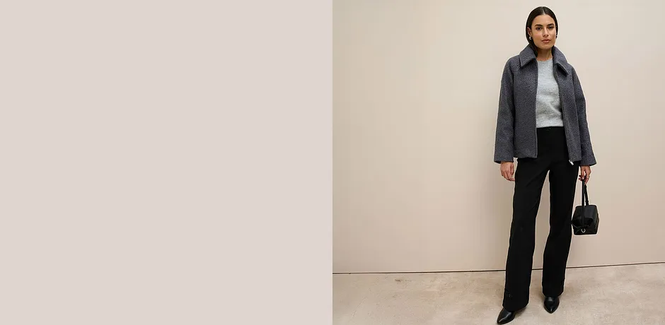 Giacca grigia, maglione grigio e pantaloni neri.