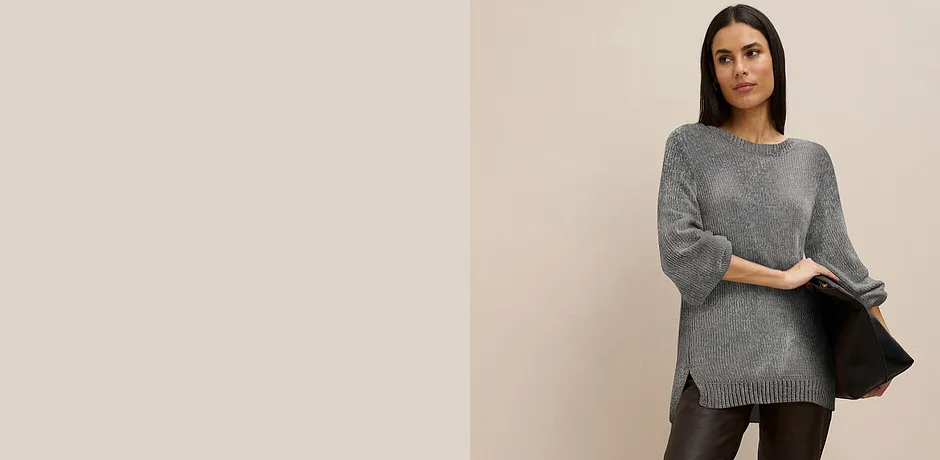 Maglione lungo grigio abbinato a pantaloni scuri.