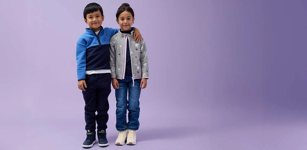 Bambini in jeans e giacche: giacca blu per lui, giacca grigia per lei.