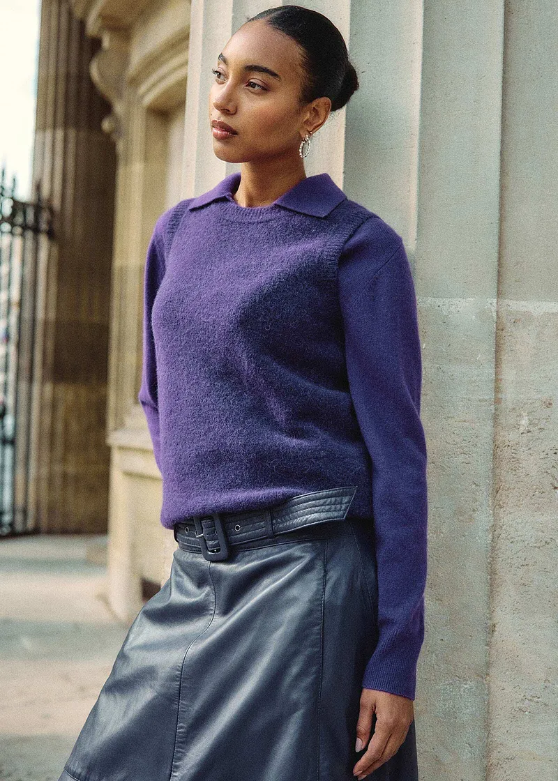 Maglione di lana viola con colletto abbinato a gonna di pelle grigia.