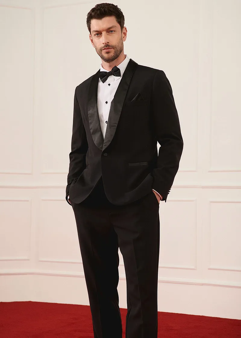 Elegante smoking nero con papillon e camicia bianca per occasioni speciali.