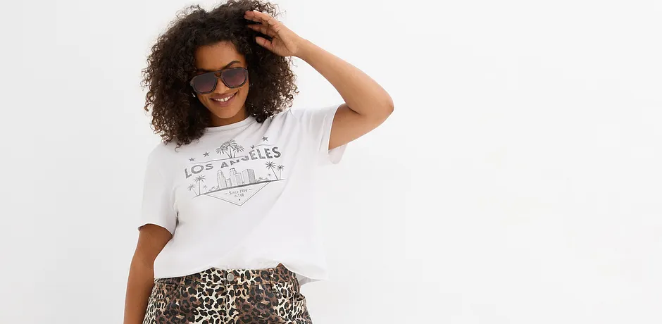 T-shirt bianca ampia con stampa, abbinata ad una gonna leopardata. Occhiali da sole come accessorio.