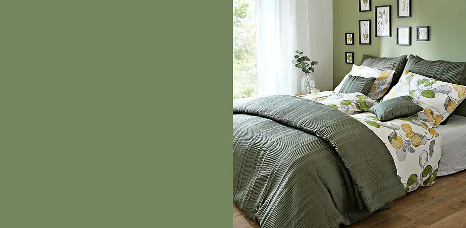 Camera da letto accogliente con lenzuola e cuscini verdi. I motivi floreali sulle lenzuola conferiscono freschezza.