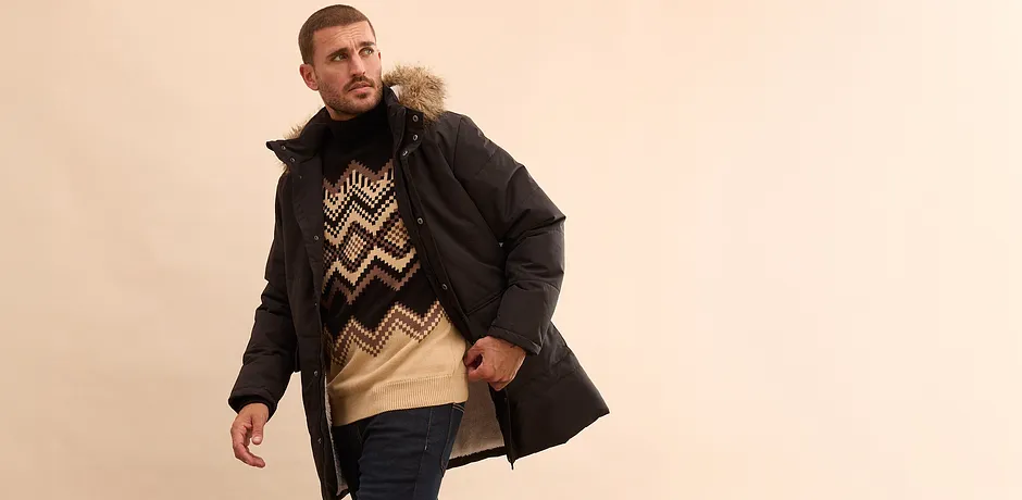 Look elegante con giacca invernale nera, maglione fantasia e jeans per le giornate fredde.