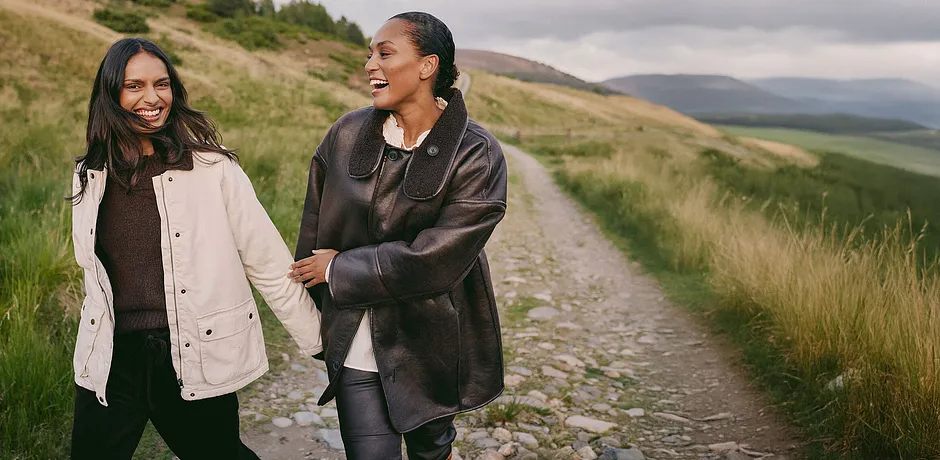 Elegante cappotto in pelle marrone con ampio collo abbinato a un top chiaro e pantaloni scuri.