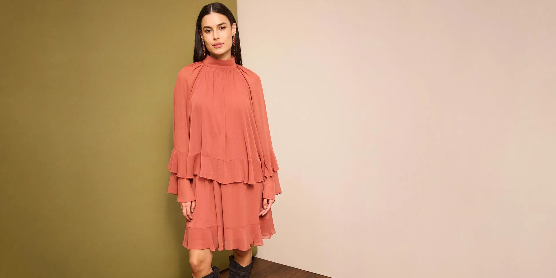 Un abito color salmone con volant e maniche larghe sottolinea la silhouette femminile.