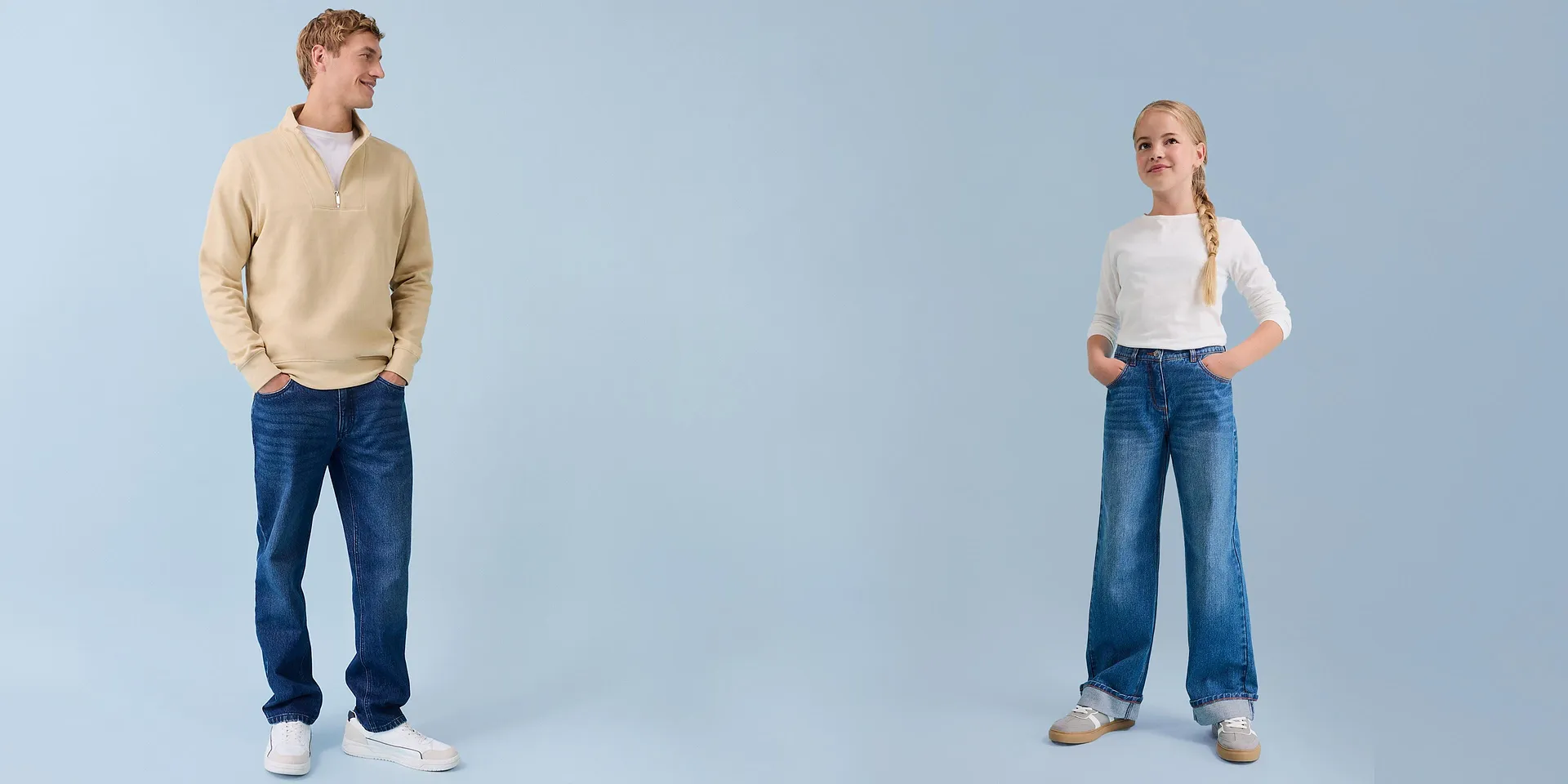 Moda casual: uomo con felpa e bambina con maglia a maniche lunghe e jeans su sfondo chiaro.