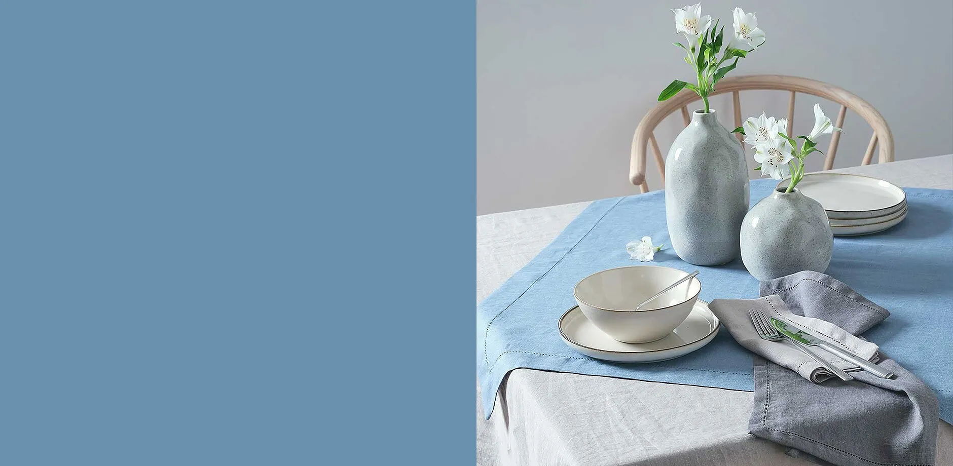 Stoviglie eleganti in tonalit&agrave; pastello chiare su tovaglia azzurra.