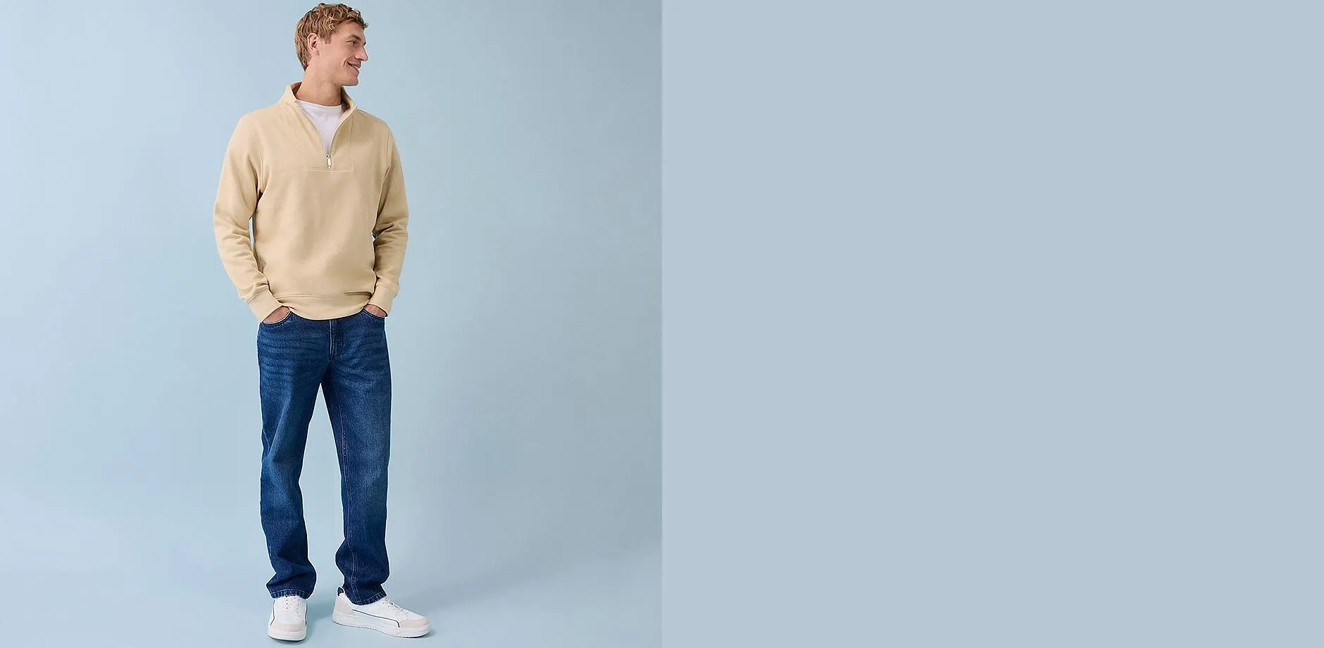 Maglione beige con zip, jeans blu e sneakers bianche: look casual da uomo per tutti i giorni.
