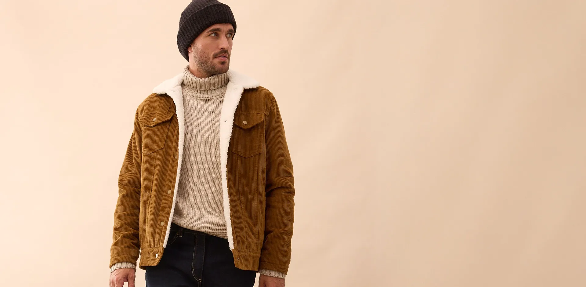 Stilvolle Kombination aus brauner Wildlederjacke, cremefarbenem Rollkragenpullover und schwarzer M&uuml;tze.