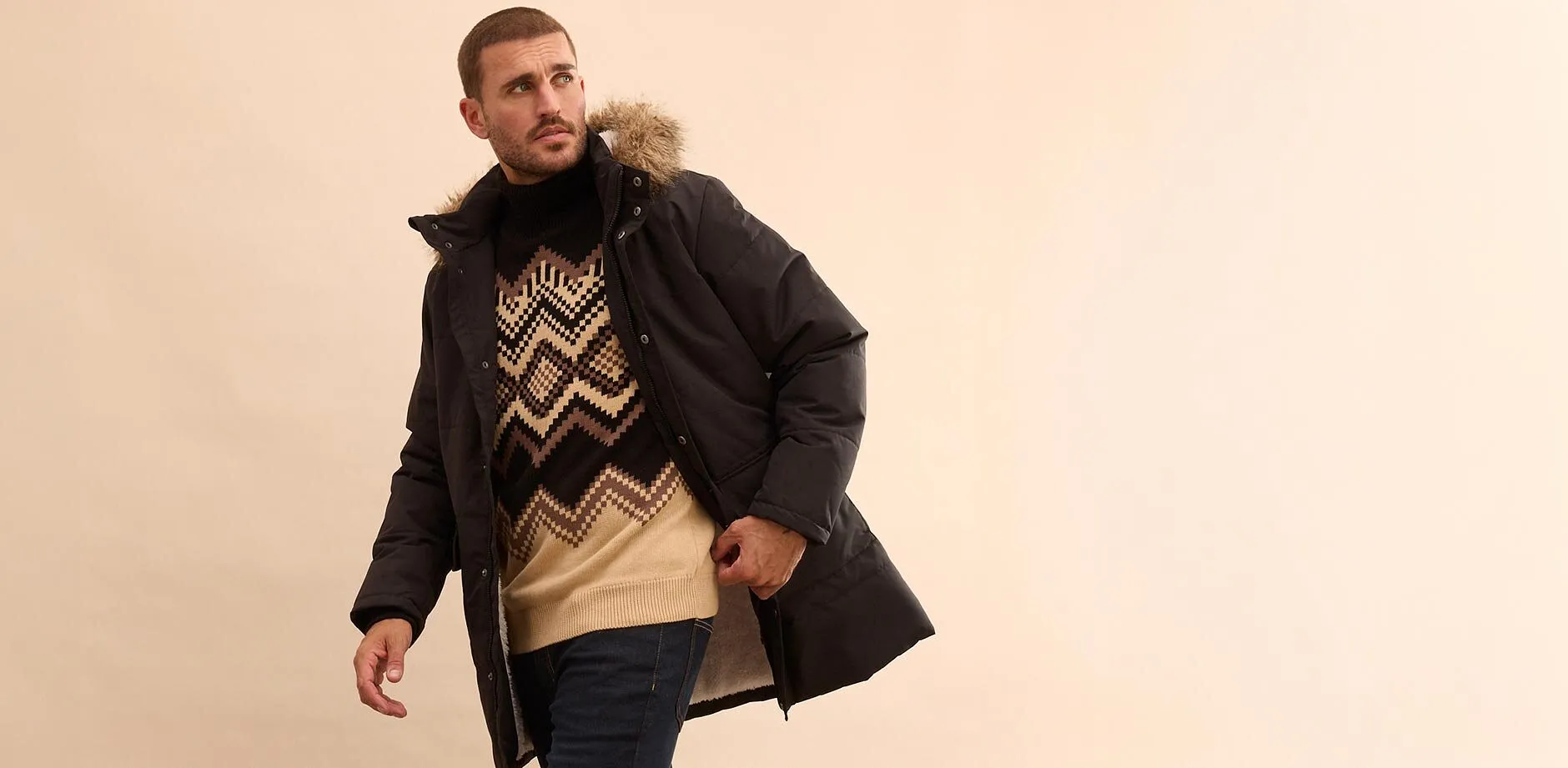 Look elegante con giacca invernale nera, maglione fantasia e jeans per le giornate fredde.