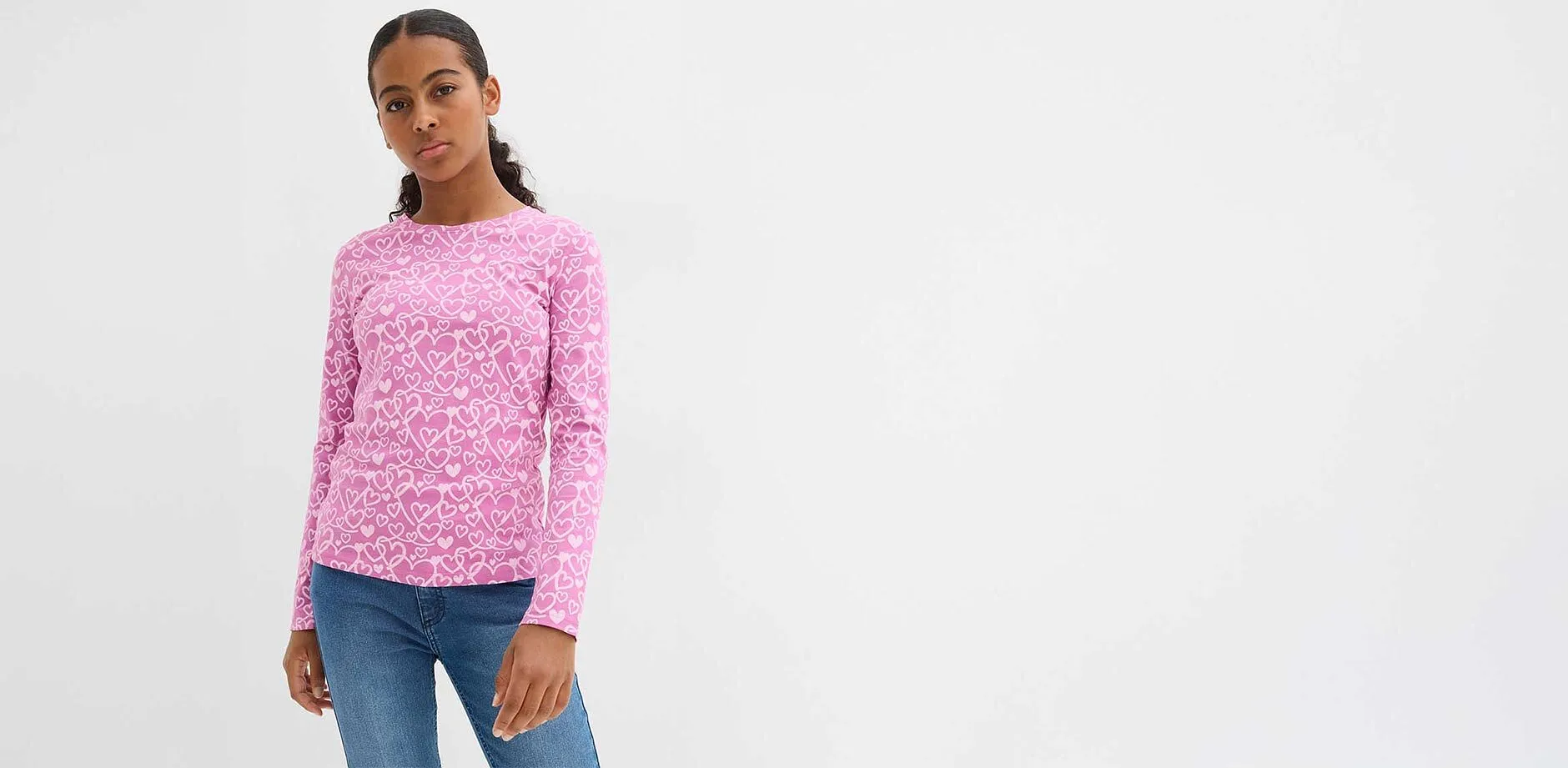 Maglione rosa con motivo leopardato bianco, jeans blu. Look casual per tutti i giorni.