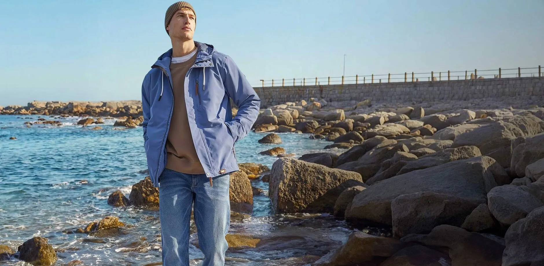 Elegante giacca blu funzionale e jeans chiari sulla spiaggia.