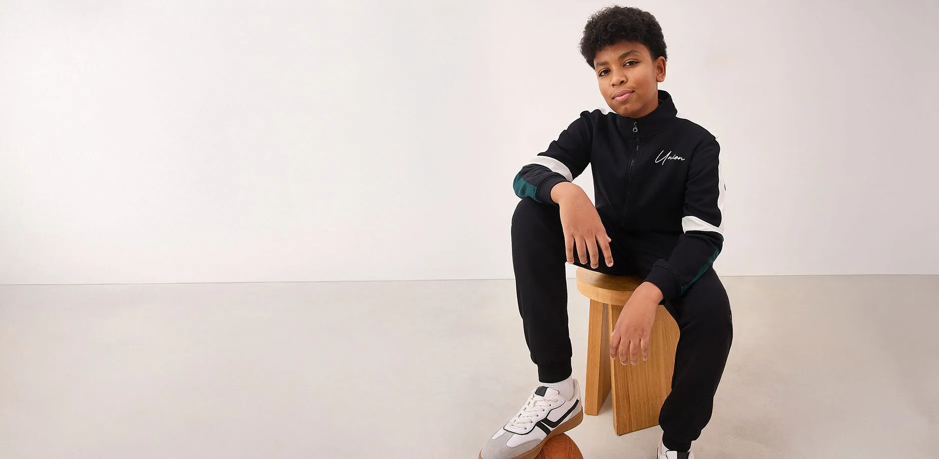 Giacca blu con logo bianco, jeans casual e scarpe da ginnastica.