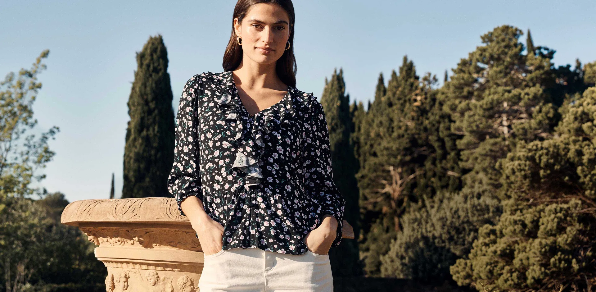 Abbinamento di camicetta fantasia e pantaloni bianchi.