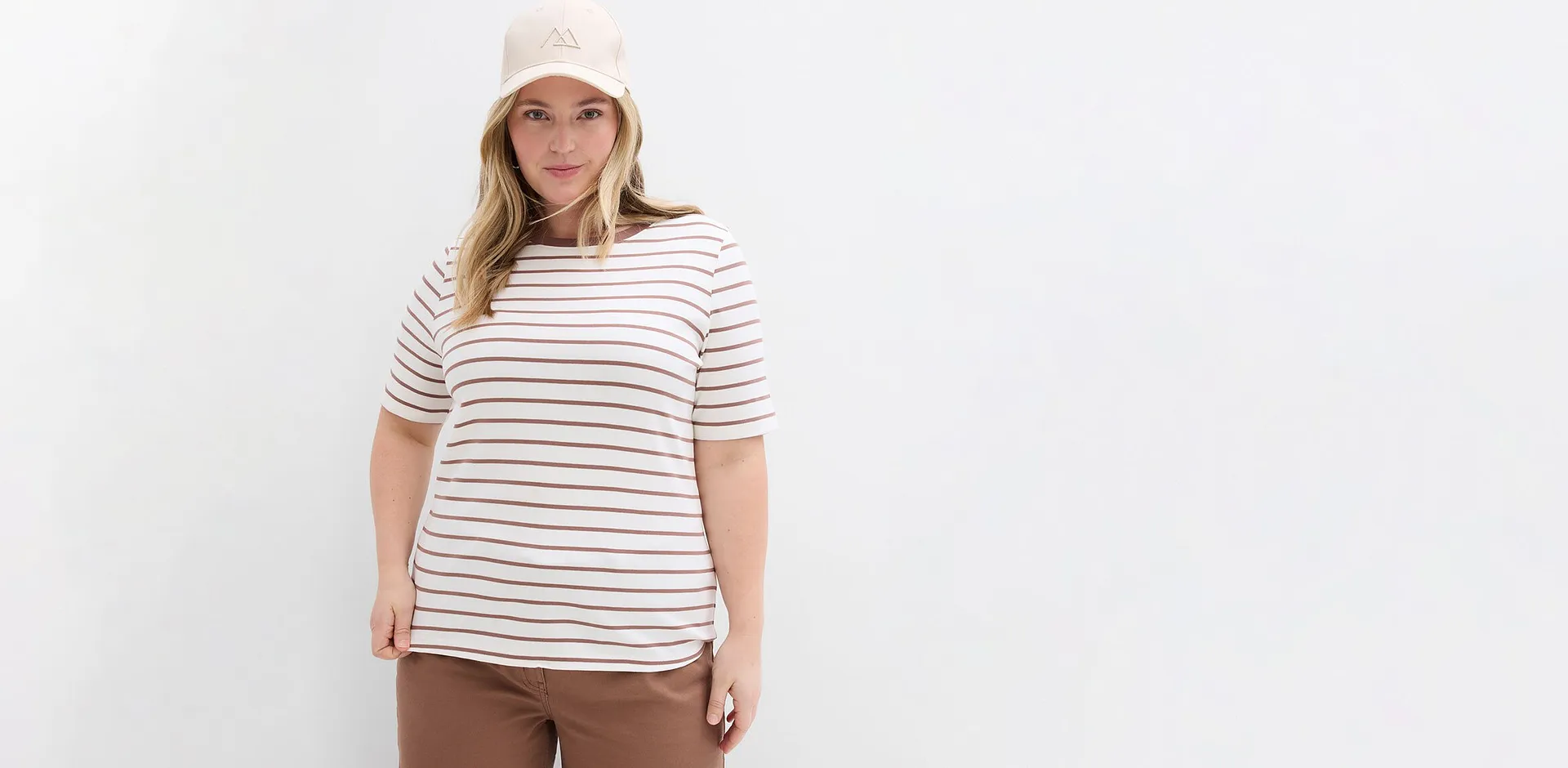 Maglietta a righe bianche e marroni abbinata a pantaloni marroni.