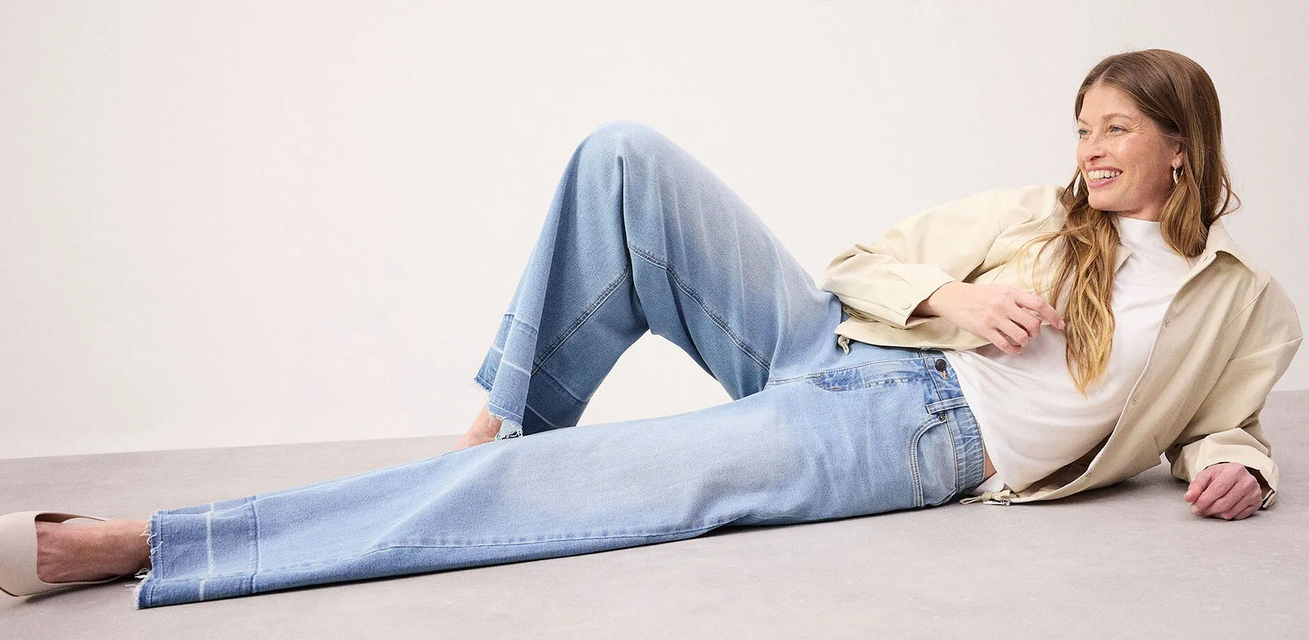 Look casual con jeans larghi, top bianco e giacca beige.