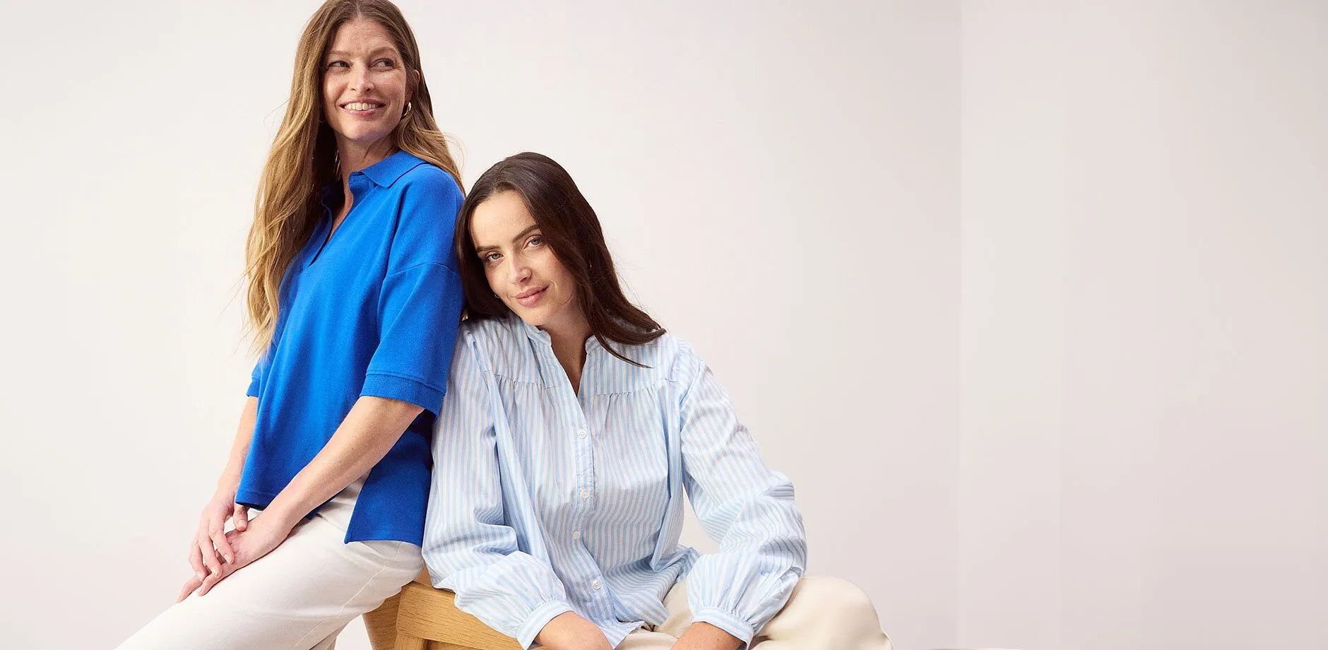 Polo blu e camicetta a righe con pantaloni bianchi: eleganza casual per l'estate.