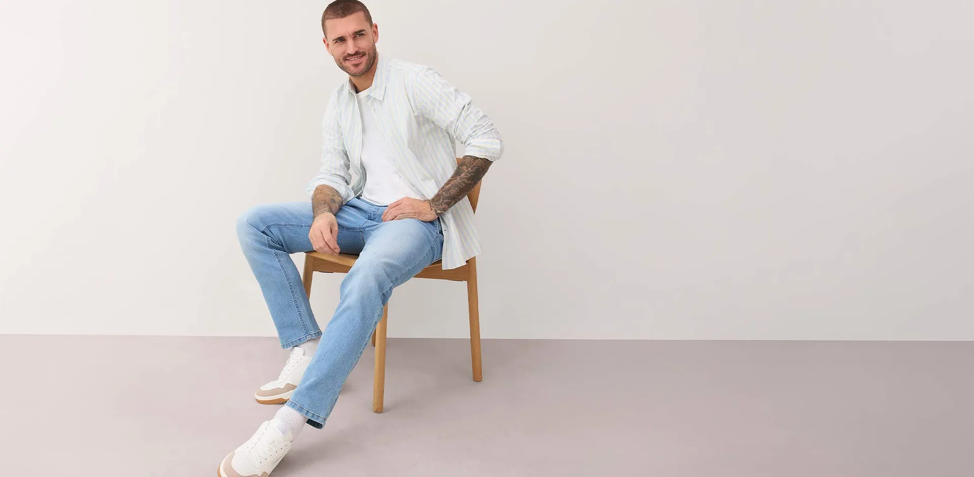 Camicia bianca a righe, jeans azzurri e scarpe da ginnastica bianche.