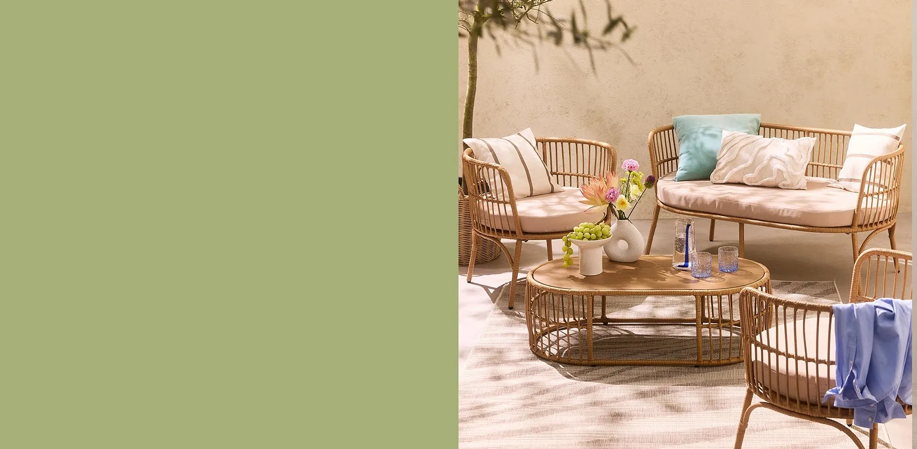 Gem&uuml;tliche Rattanm&ouml;bel mit hellen Kissen und Decken laden zum Entspannen im Freien ein.