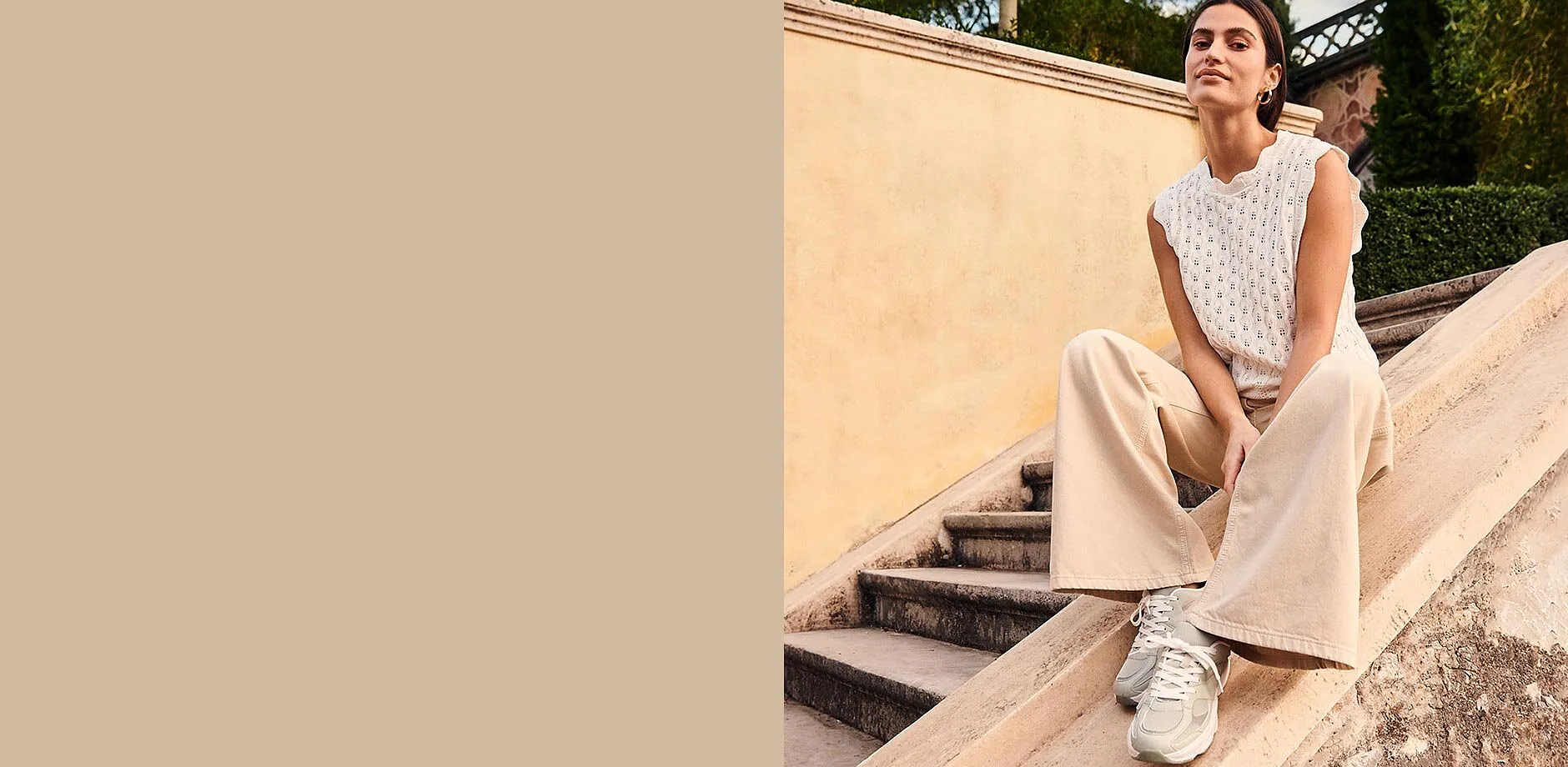 Outfit composto da top bianco, pantaloni larghi beige e comode sneakers.