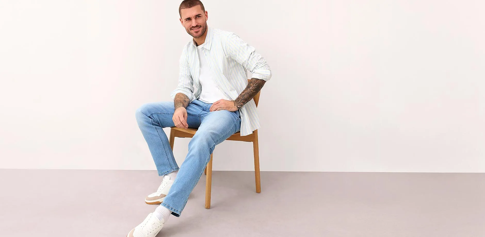 Camicia bianca a righe, jeans azzurri e scarpe da ginnastica bianche.