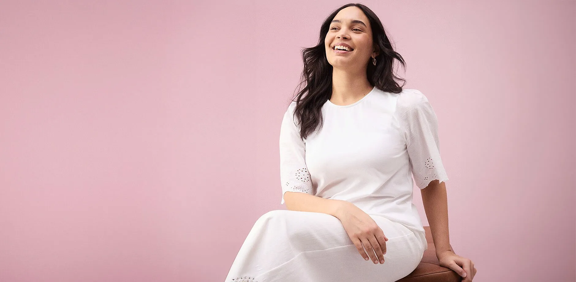 Una donna radiosa con pantaloni blu cropped e maglietta a righe.