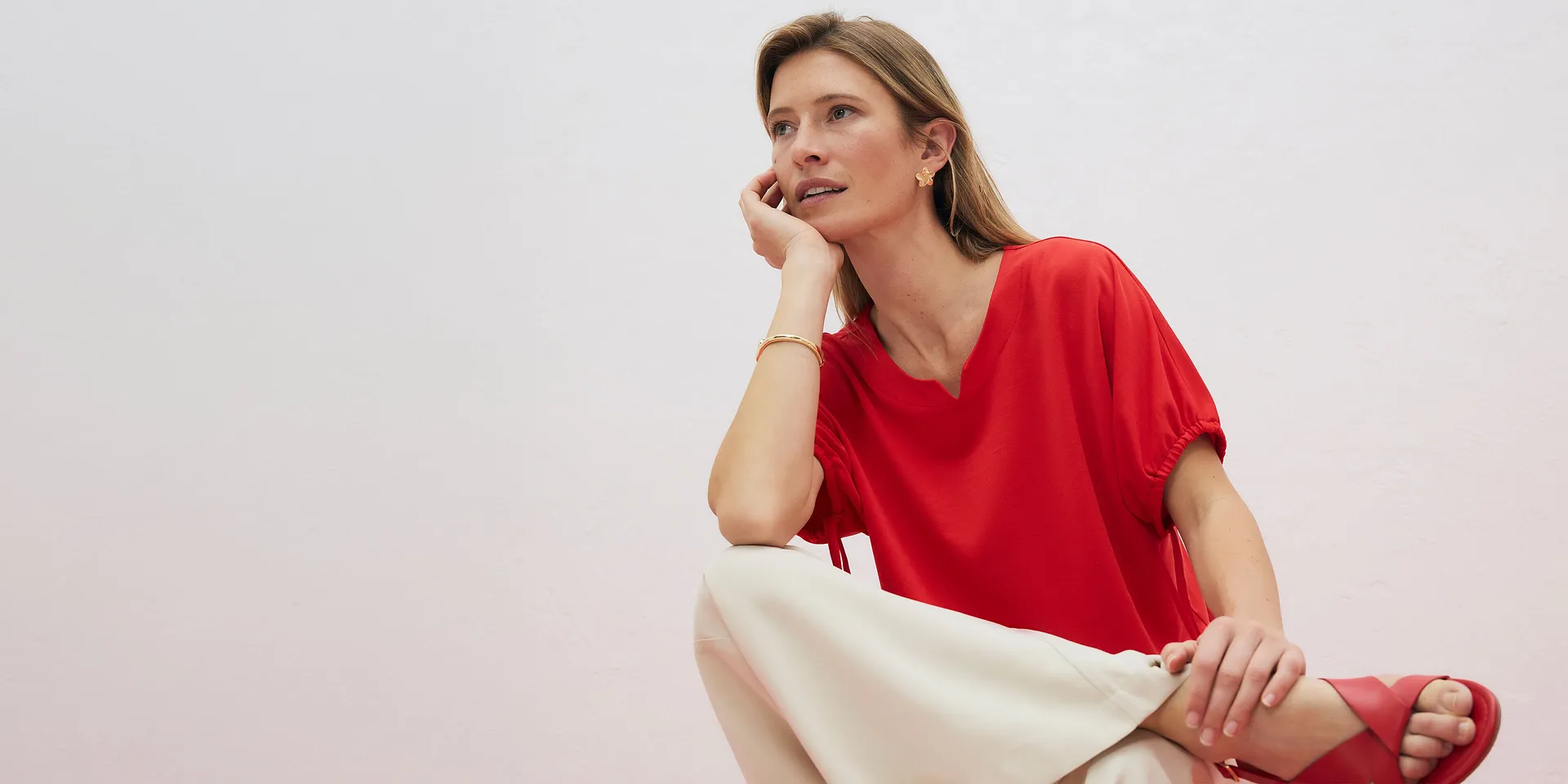 Elegante maglietta rossa con scollo a V, abbinata a pantaloni chiari.