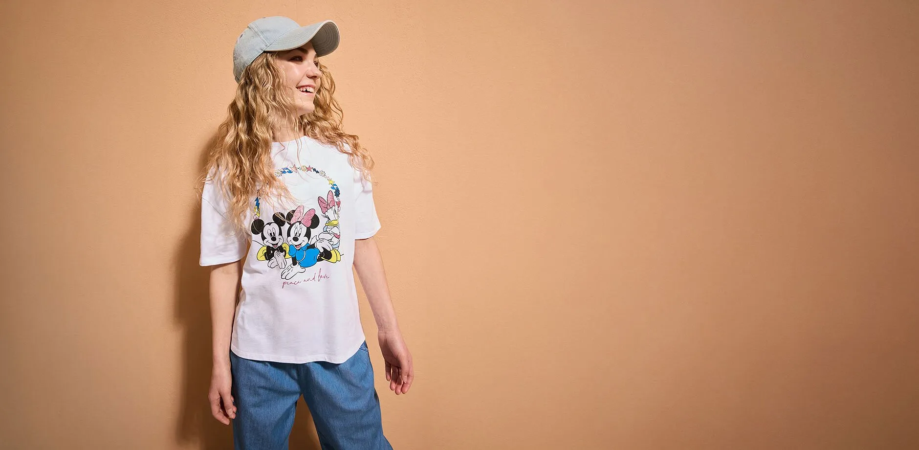 Uno stile streetwear disinvolto con maglietta stampata, jeans e cappellino da baseball. Moda estiva informale per tutti i giorni.
