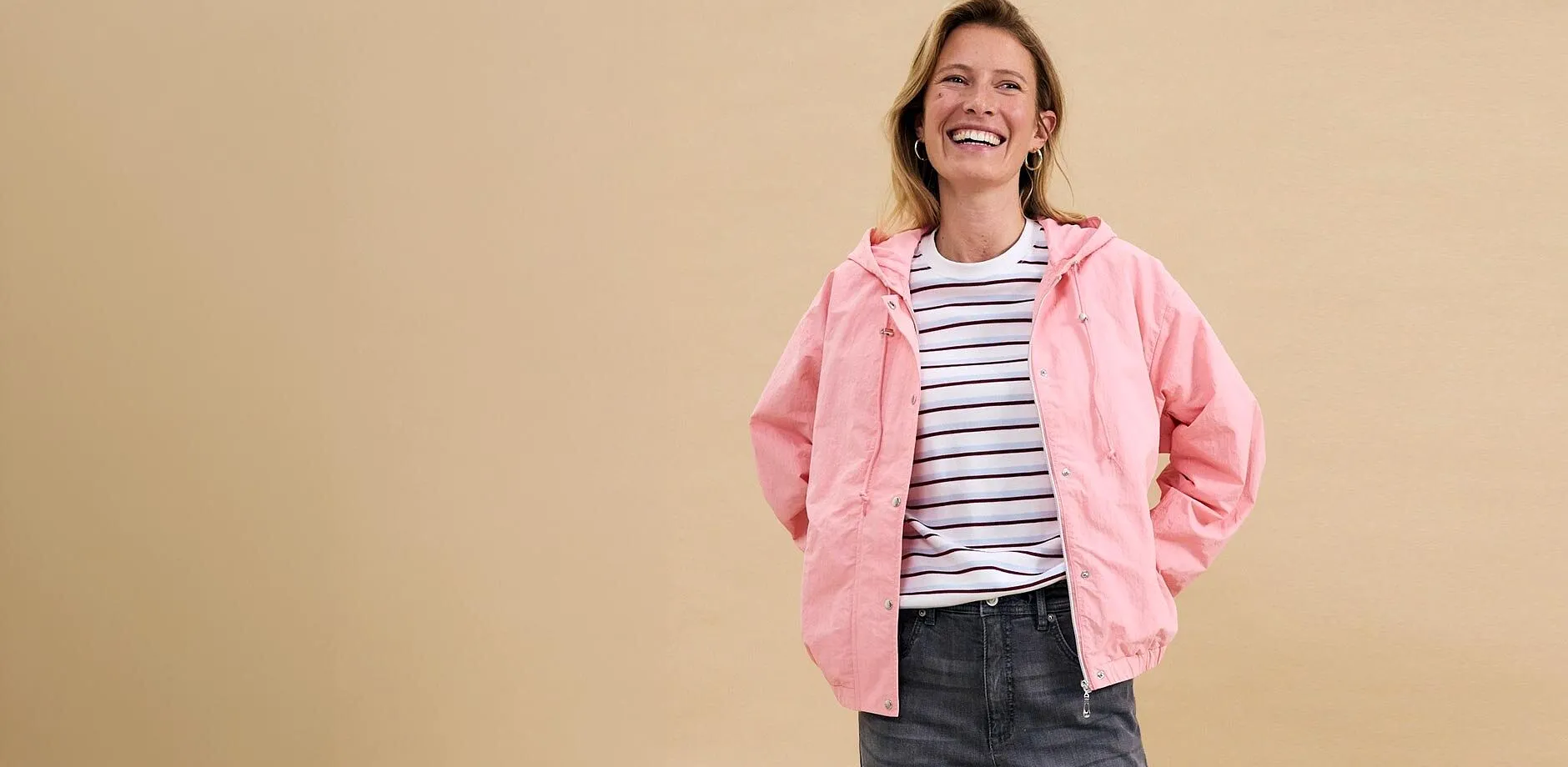 Giacca rosa sopra una maglietta a righe, abbinata a jeans grigi: un look casual per il tempo libero.