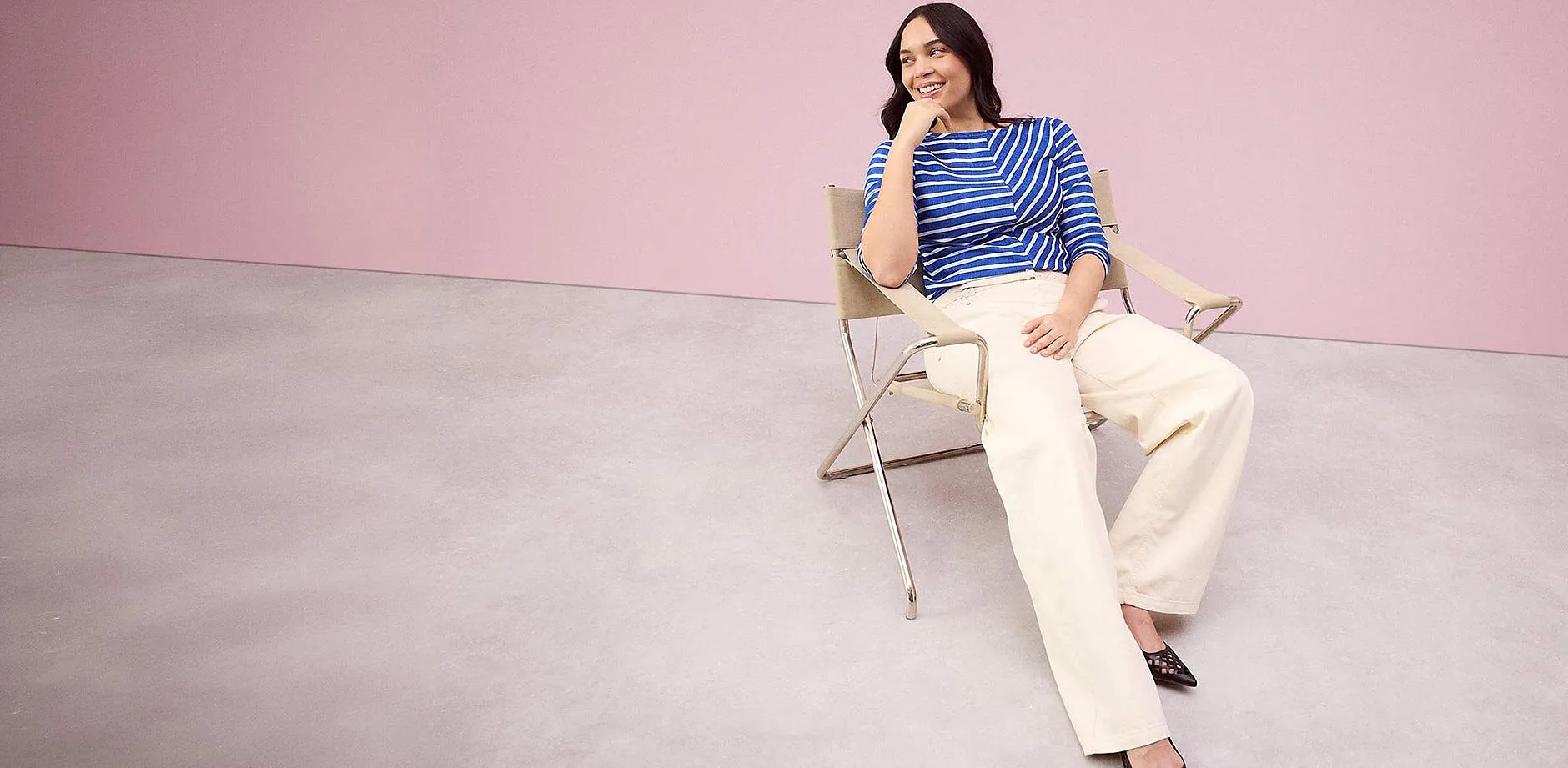 Una maglia a righe blu e bianche abbinata a pantaloni larghi color crema.