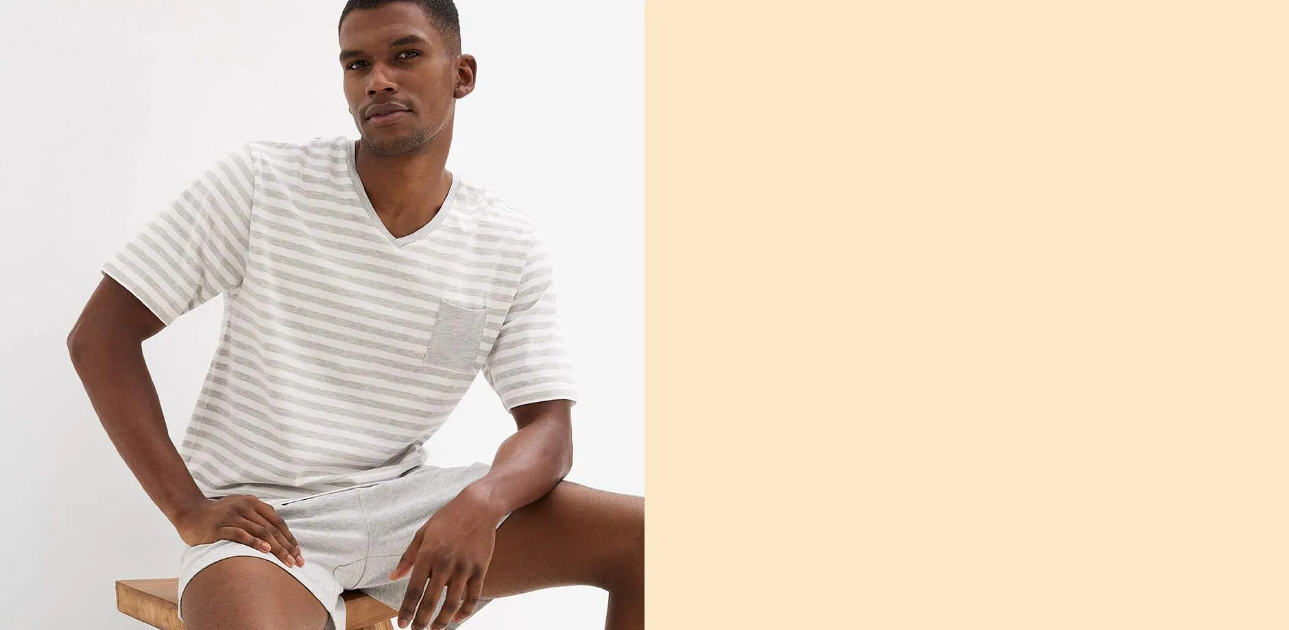 Maglietta a righe con scollo a V in tonalit&agrave; chiare, abbinata a pantaloncini chiari.