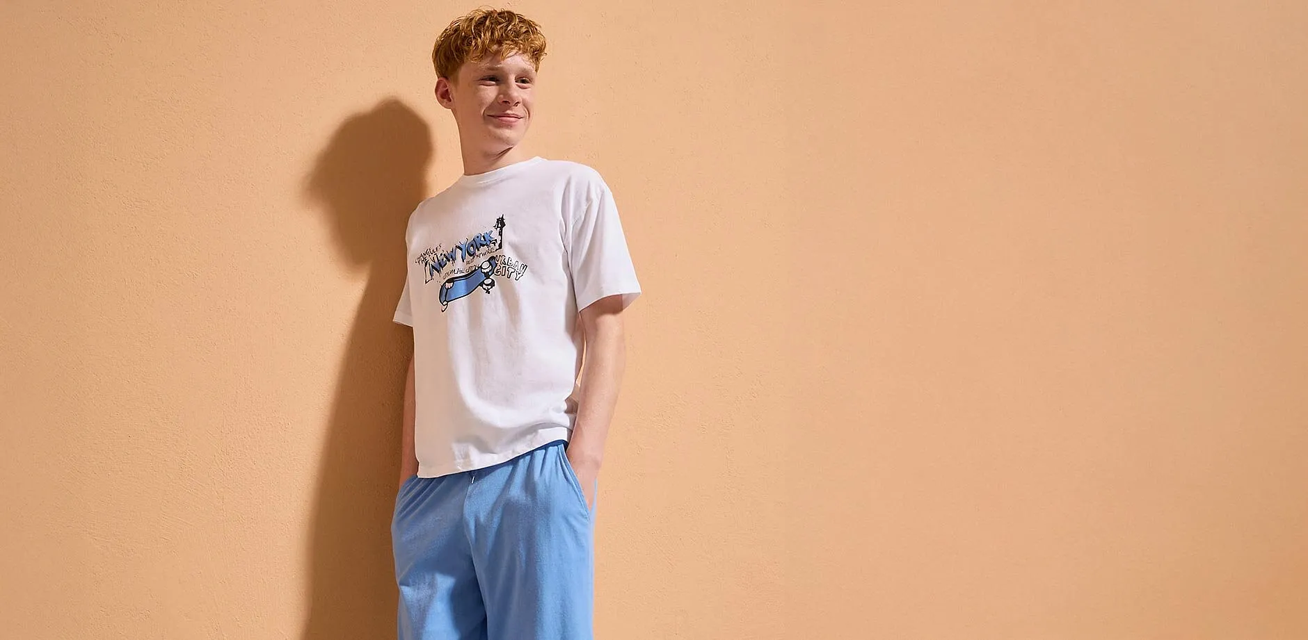 Un ragazzo indossa una maglietta bianca con una stampa.