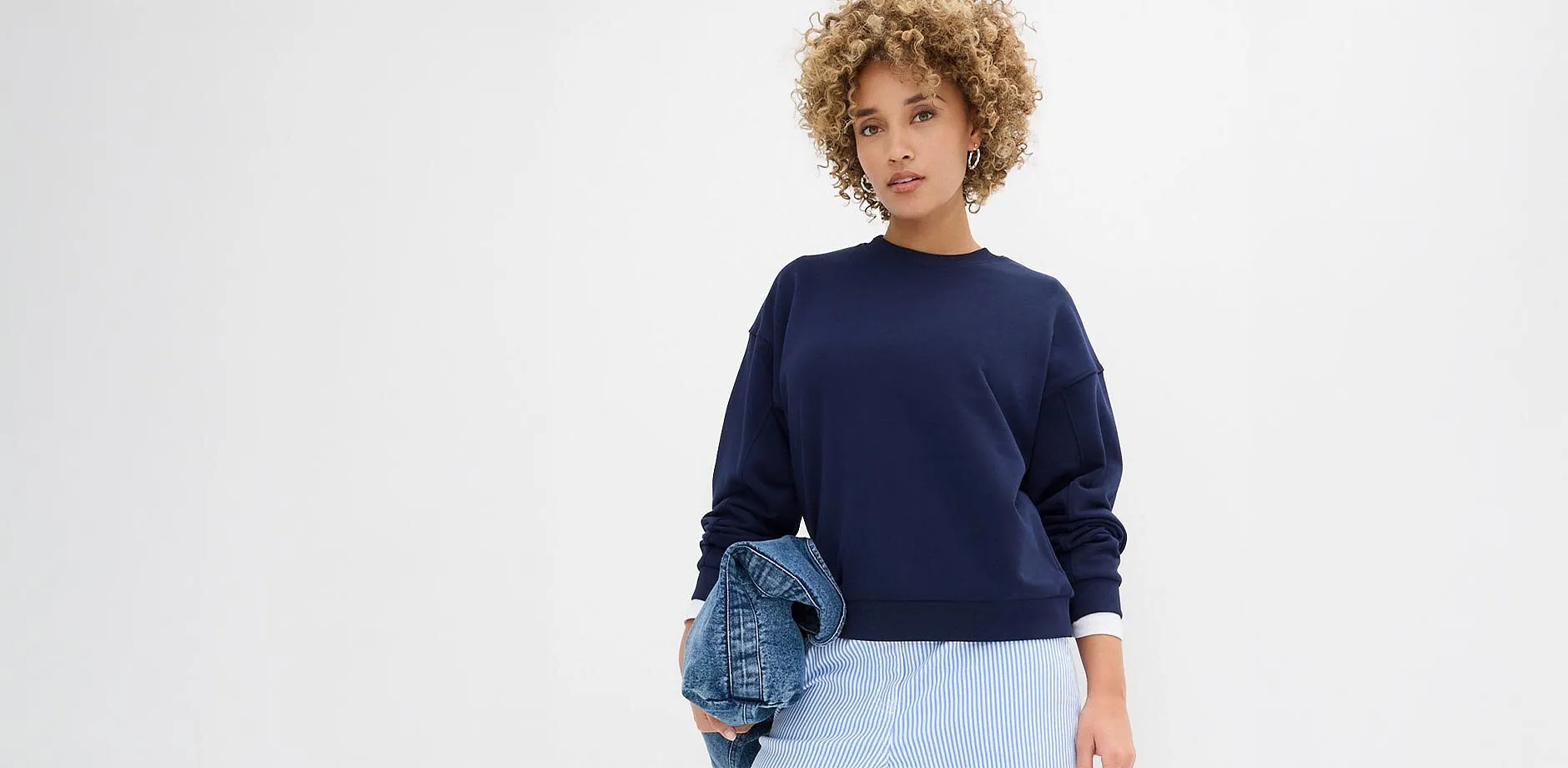 Felpa oversize blu con pantaloni a righe.