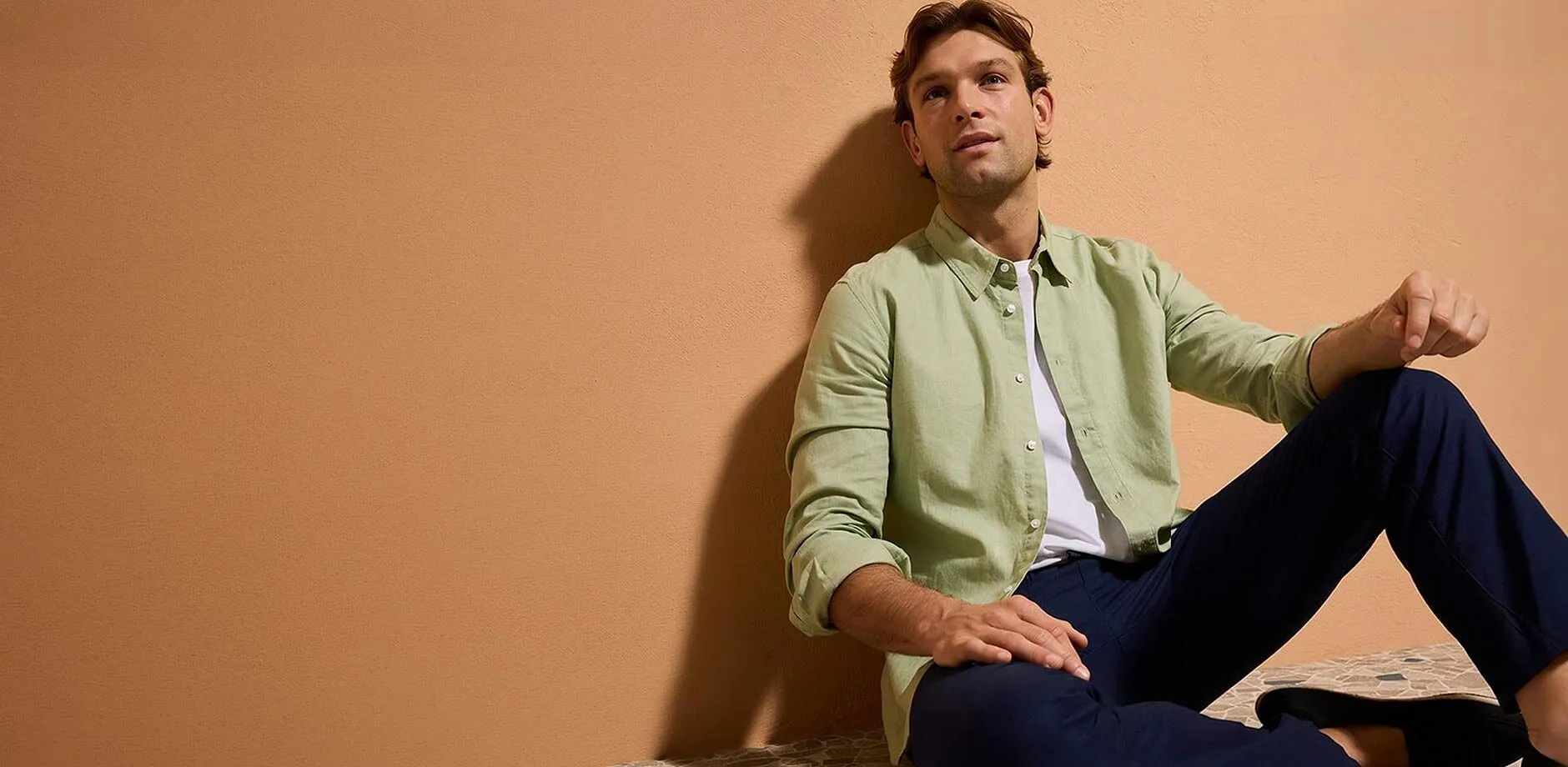 Camicia verde pastello, pantaloni blu scuro e scarpe casual.