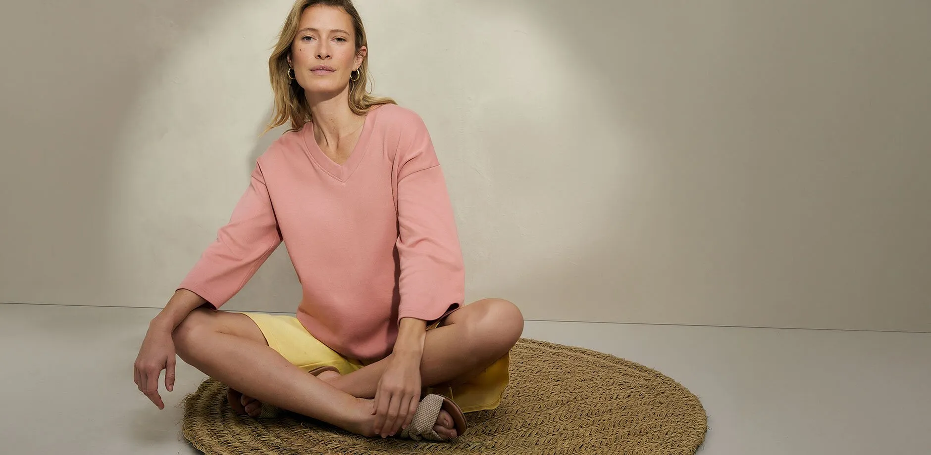 Una donna indossa una blusa rosa abbinata a shorts gialli.