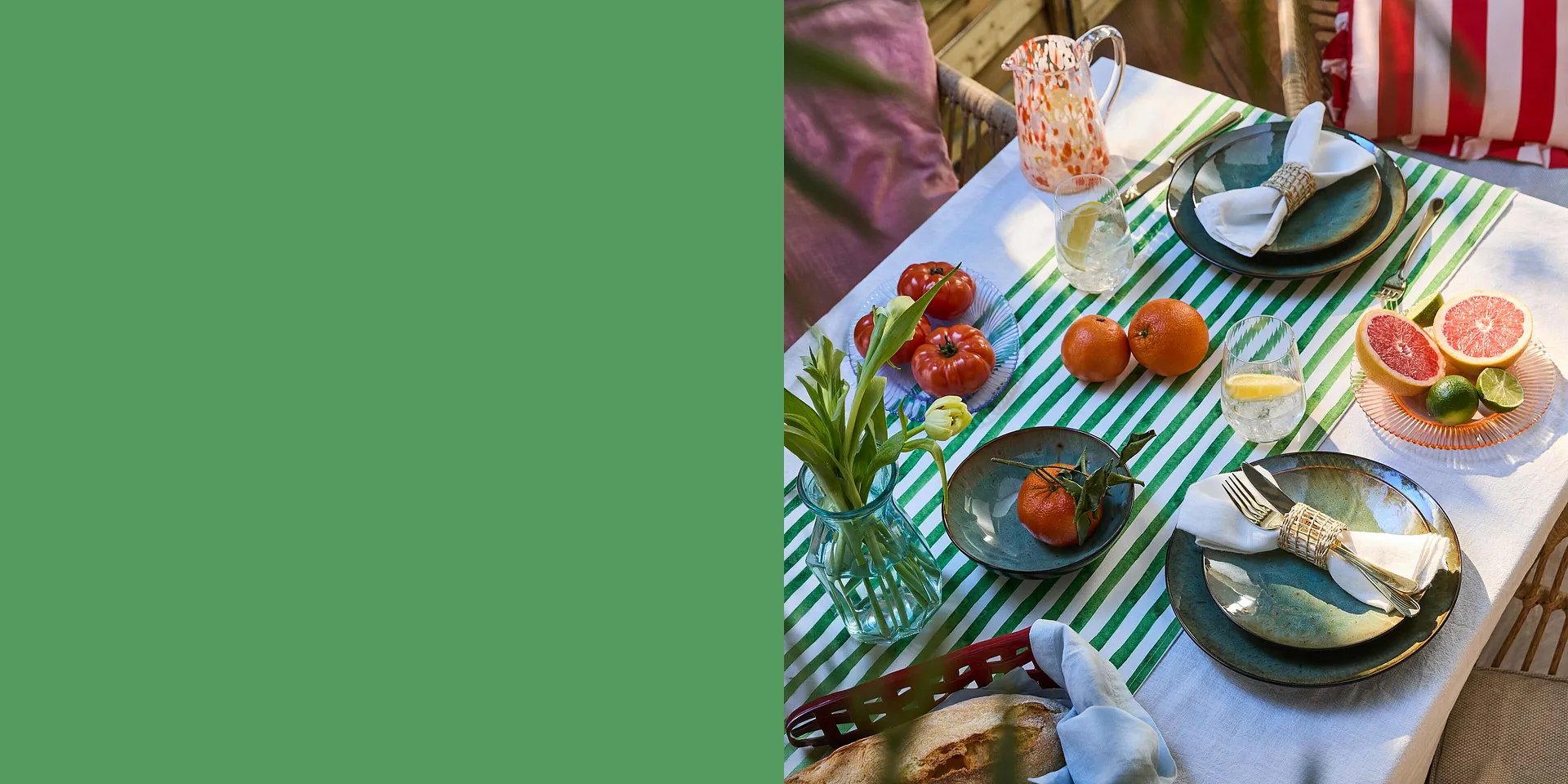 Una tovaglia a righe impreziosisce la tavola estiva con stoviglie colorate e frutta fresca.