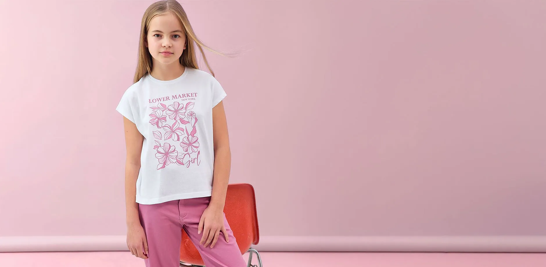 Maglietta bianca con motivi floreali rosa e pantaloni rosa.