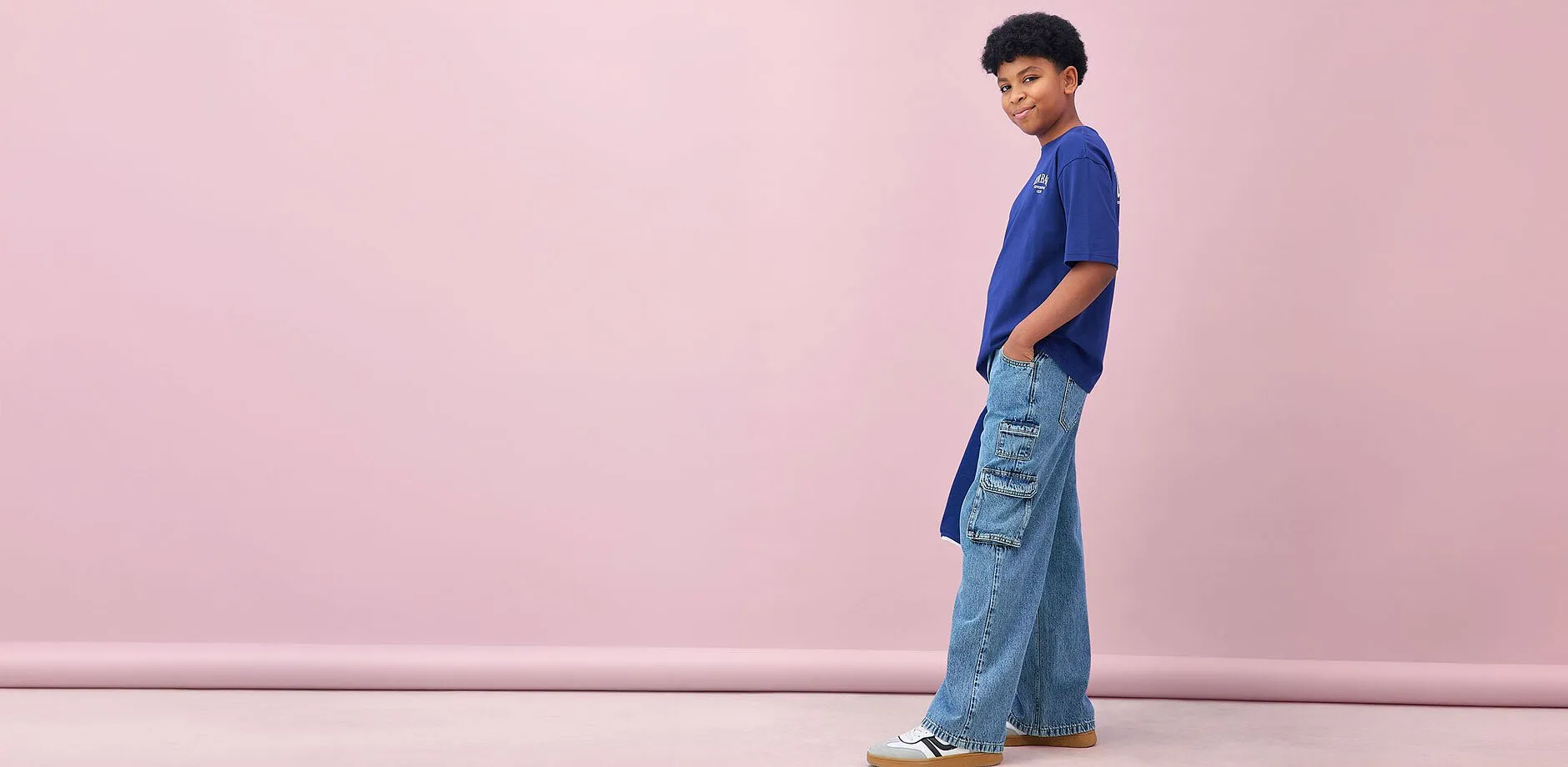Un ragazzo indossa una maglietta blu e dei jeans cargo larghi.