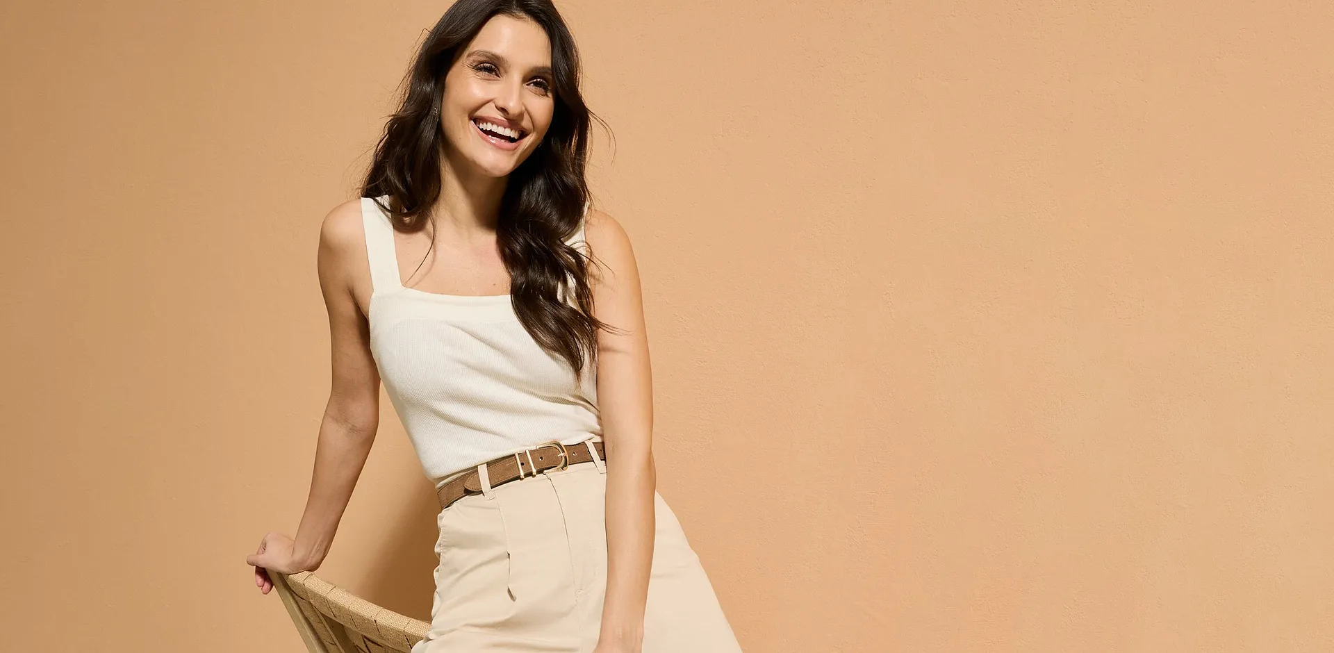 Top bianco e pantaloni beige in stile minimalista.