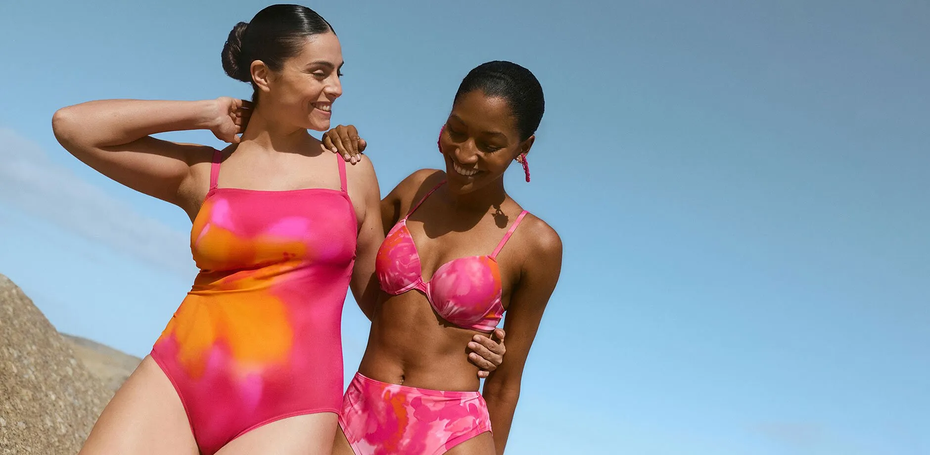 Due donne in costume da bagno e bikini rosa shocking sulla spiaggia.