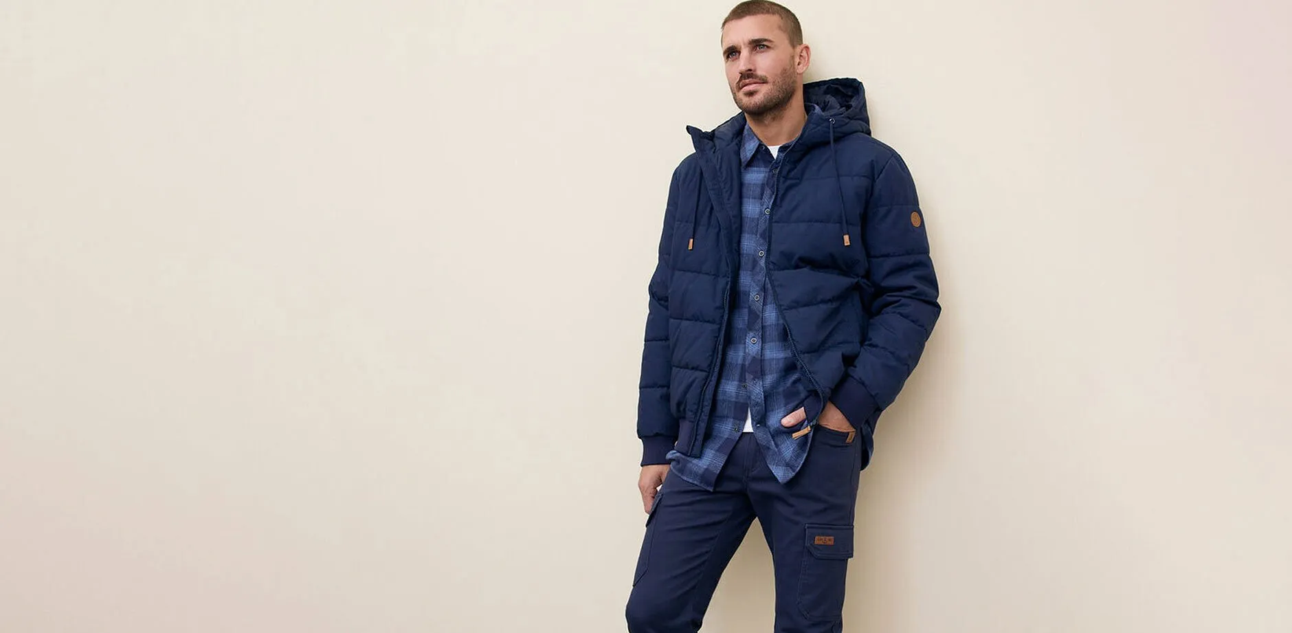 Giacca trapuntata blu navy, jeans e camicia a quadri blu.