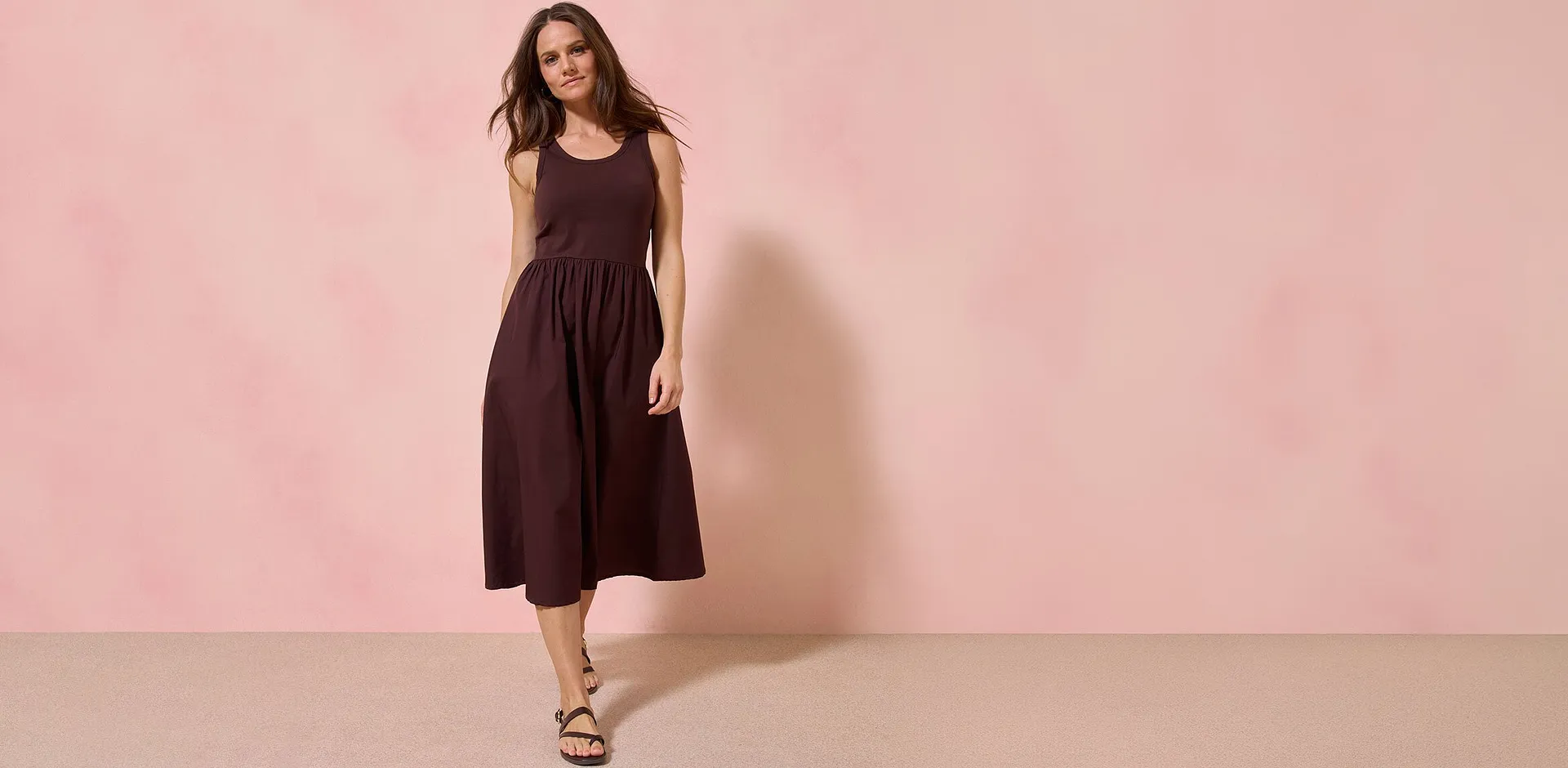 Abito midi marrone scuro con spalline e dal taglio femminile.