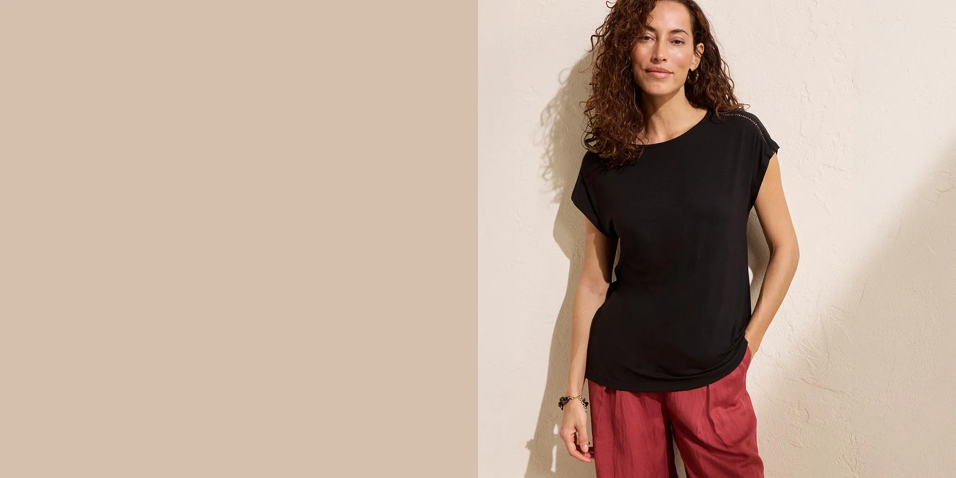 Una donna indossa una maglia nera a maniche corte e pantaloni rossi.